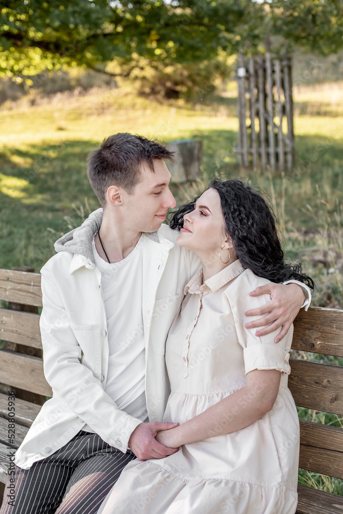 A couple in love, a guy and a girl sit on a bench and caress each other, kiss A couple in love, a guy and a girl sit on a bench and caress each other, kiss