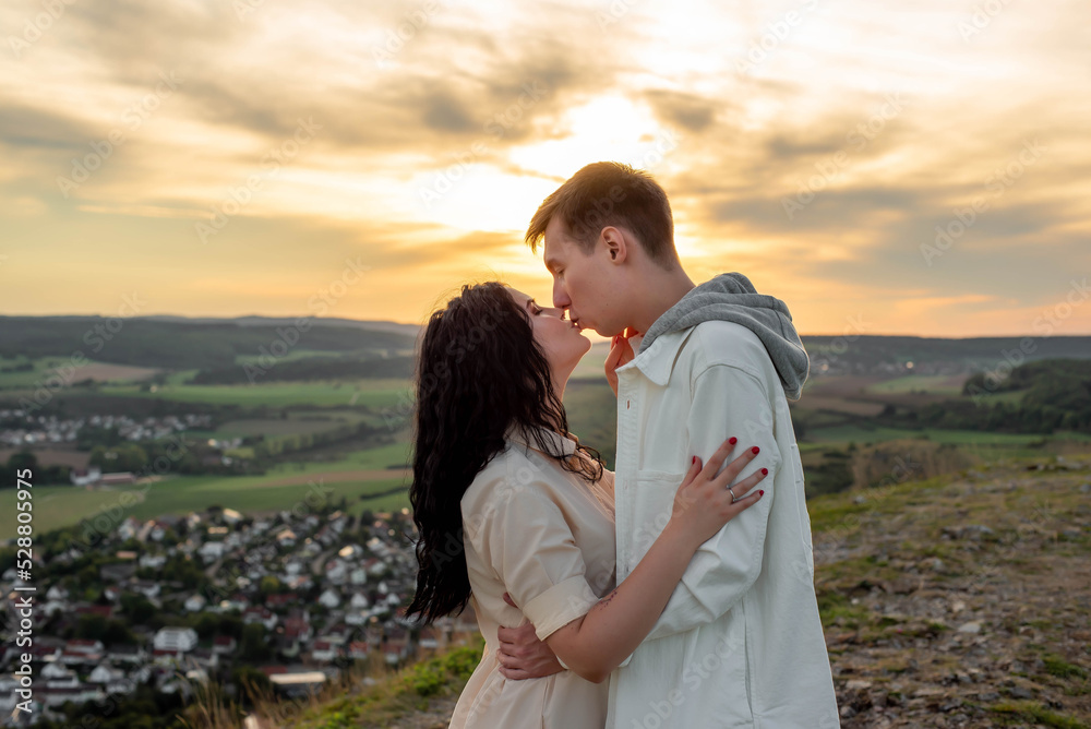 A couple in love stands on a mountain at sunset