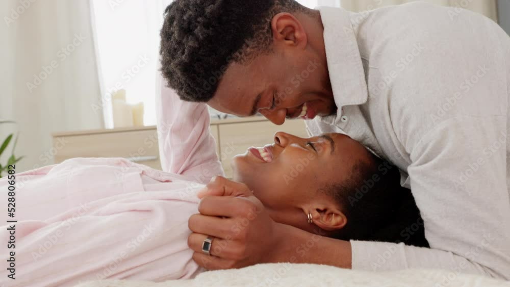 Happy, love and couple in a bedroom kiss and laughing in happiness, bonding time together at home. Young black man and woman kissing on a bed with a smile in joy for caring relationship and marriage Happy, love and couple in a bedroom kiss and laughing in happiness, bonding time together at home. Young black man and woman kissing on a bed with a smile in joy for caring relationship and marriage