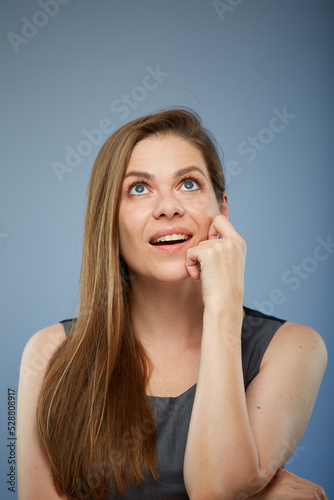 Business woman thinking and looking up touching her face. isolated on blue.