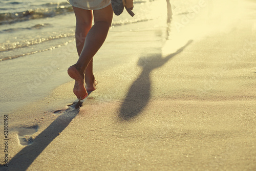 young woman walking on the beach in sunset light