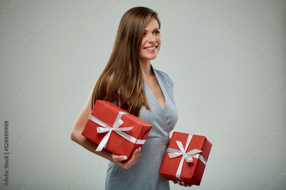 Happy business woman in dress holding two red gifts isolated on gray. Girl looking away. Happy business woman in dress holding two red gifts isolated on gray. Girl looking away.