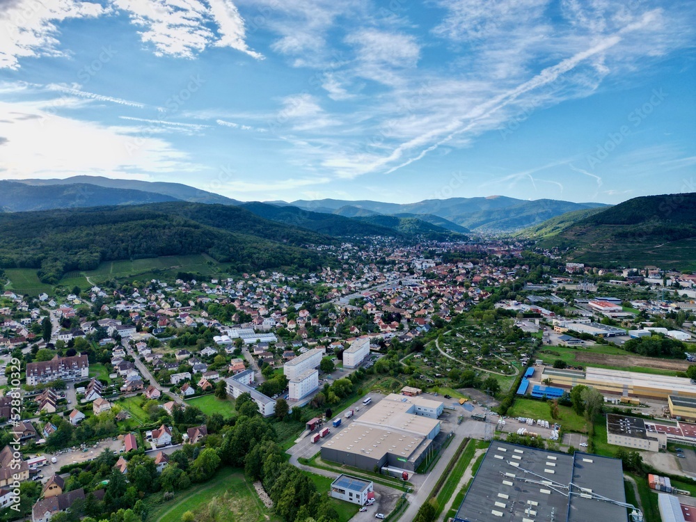 Panoramic aerial drone view of the entrance of the Florival valley and Guebwiller on a sunny summer day, with a part of the Industrial Zone of Soultz-Haut-Rhin