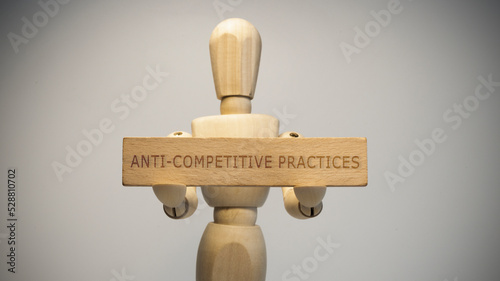 Anti-competitive practices written on wooden surface. Close-up in the studio. social issues. photo
