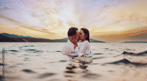 Romantic couple kissing in the sea at sunset. High quality photo