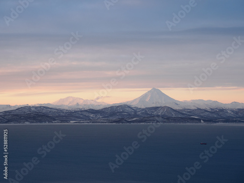 Distant view of Vilyuchik stratovolcano behind sea waters on a sunset