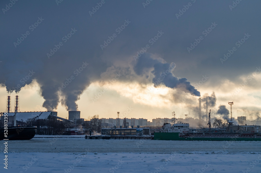 Industrial landscape on a frozen river. Winter landscape at the docks. Winter navigation in St. Petersburg.