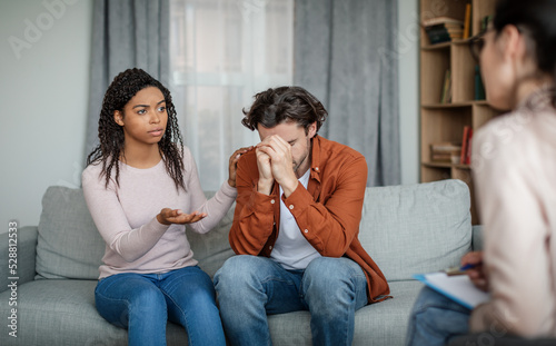 Murais de parede Sad black wife calms depressive european husband on consultation with psychologi