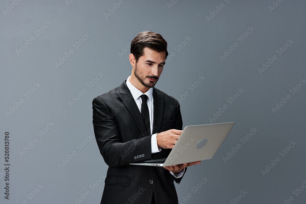 Man business looks into laptop and works thoughtfully online via internet in business suit video call business talks on gray background copy place Man business looks into laptop and works thoughtfully online via internet in business suit video call business talks on gray background copy place