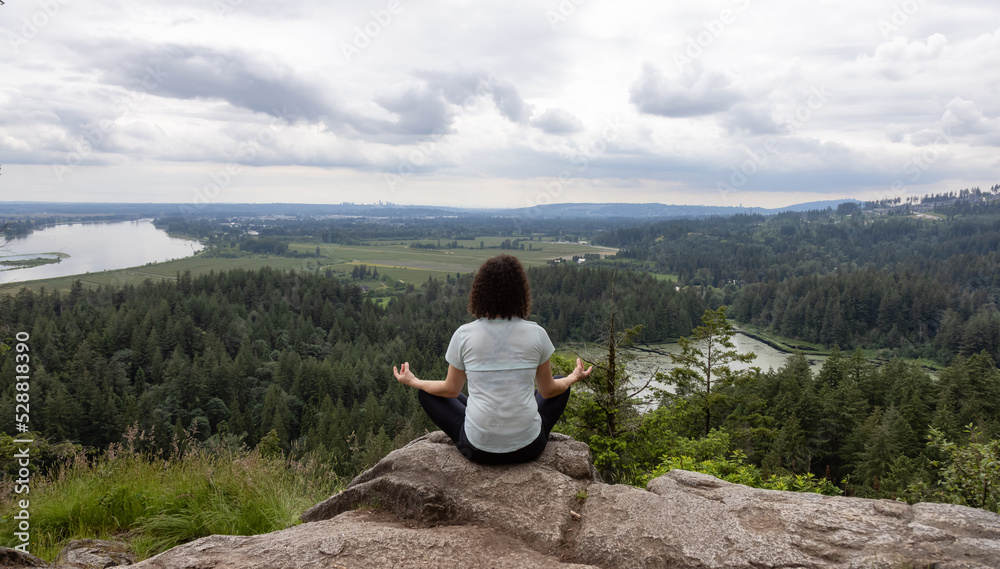 Adventurous Woman in Meditation overlooking the Canadian Nature Landscape. Minnekhada Regional Park, Coquitlam, Vancouver, British Columbia, Canada.