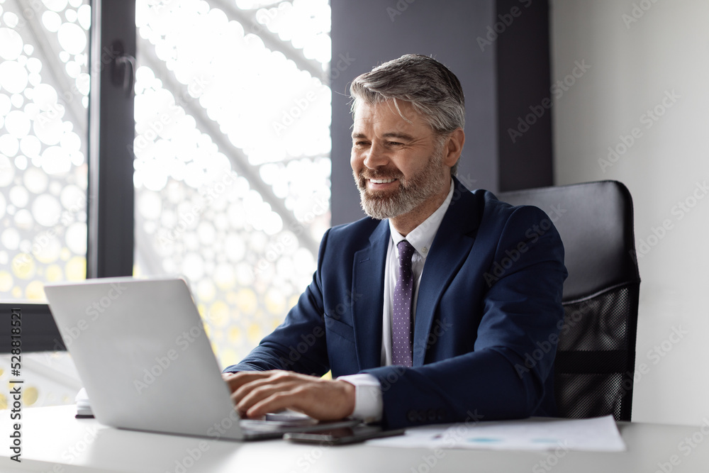Portrait Of Smiling Middle Aged Businessman Working With Laptop Computer In Office Portrait Of Smiling Middle Aged Businessman Working With Laptop Computer In Office