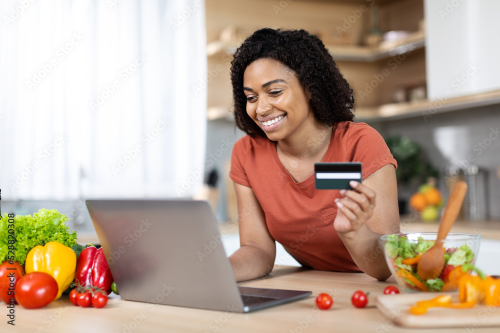 Satisfied young african american lady with laptop and credit card buy purchases remote, enjoy huge sale