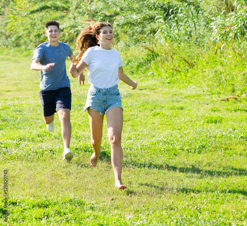 Laughing teenagers playing outdoors funning at grass on summer day © JackF