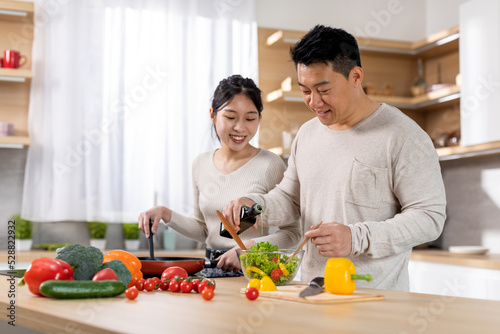 Cheerful korean husband and wife making vegetable salad