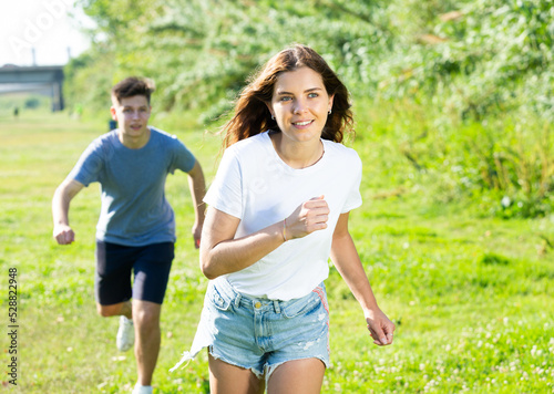 Fototapeta Naklejka Na Ścianę i Meble -  Young man and girl are running on the grass together