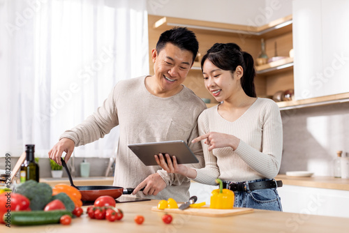 Smiling asian couple checking recipes on Internet