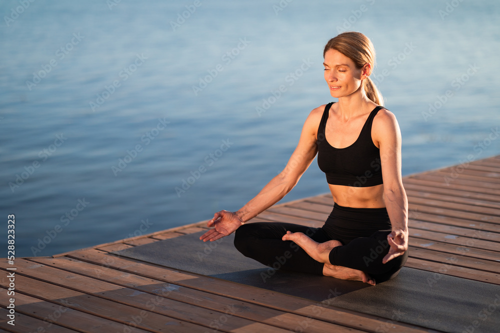 Wellbeing Concept. Beautiful Middle Aged Female In Activewear Meditating Outdoors