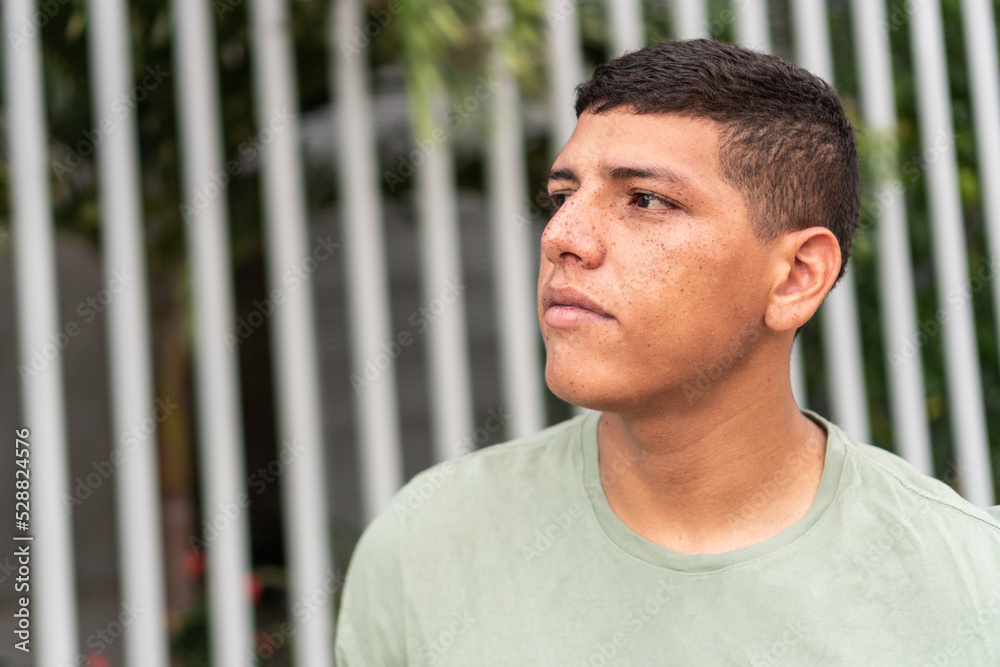Portrait of a man with freckles looking to the side while standing on the street. Portrait of a man with freckles looking to the side while standing on the street.