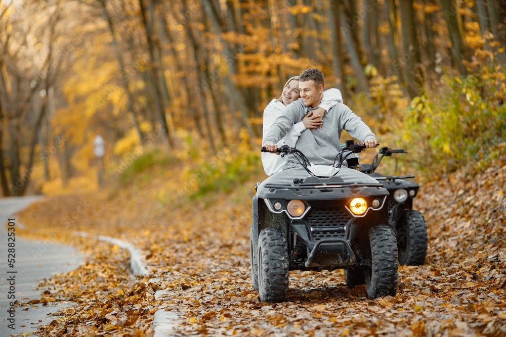 Man and woman driving quad bike in autumn forest