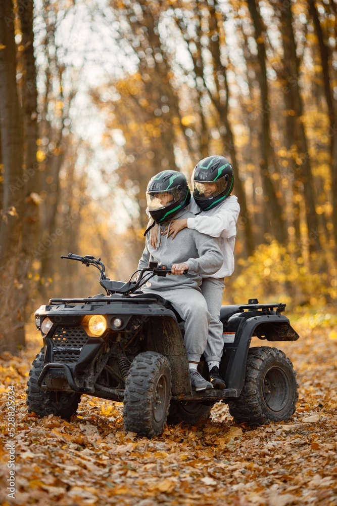 Man and woman driving quad bike in autumn forest