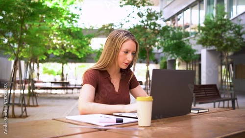 Student woman doing a university porject on her laptop at the campus photo