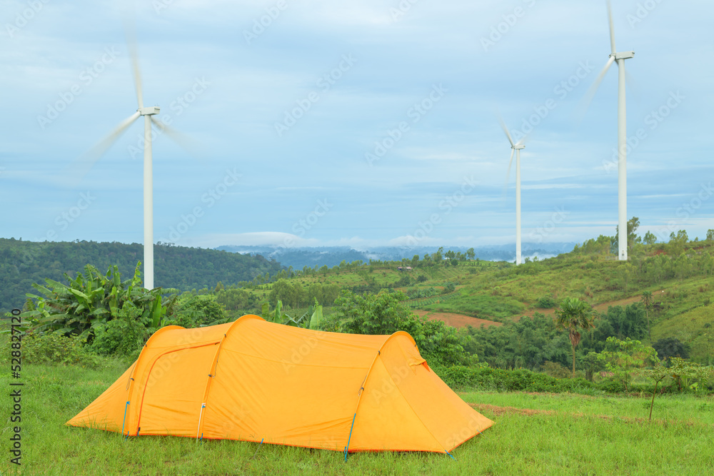 Camping and tent middle of the meadow in beautiful wind generators under blue sky.
