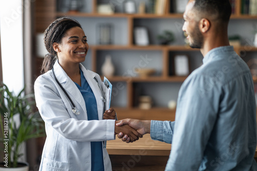 Cheerful african american woman doctor greeting patient photo