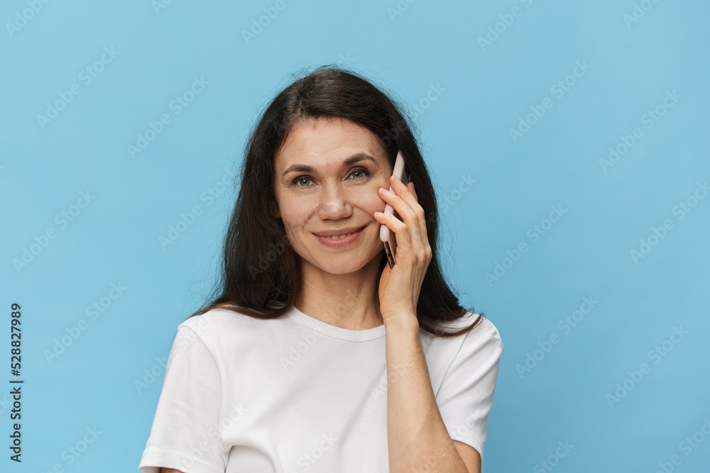 portrait of a nice, beautiful, pleasant woman in a white t-shirt talking on the phone smiling broadly portrait of a nice, beautiful, pleasant woman in a white t-shirt talking on the phone smiling broadly