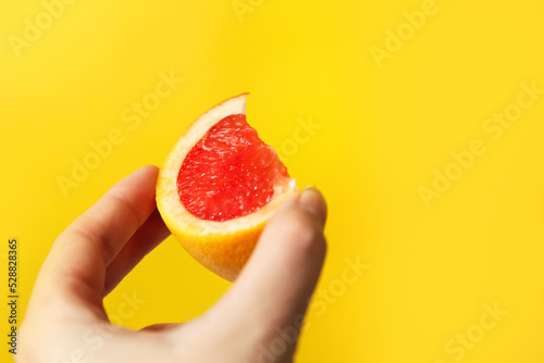 Defocus female hand holding piece of a red grapefruit. Healthy food concept.  Fresh orange juice. Vegan, vegetarian concept. Banner with copy space. Out of focus