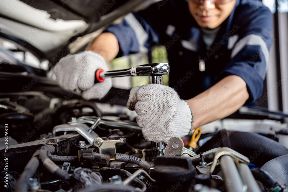 Auto mechanic repairman using a socket wrench working engine repair in the garage, change spare part, check the mileage of the car, checking and maintenance service concept. Auto mechanic repairman using a socket wrench working engine repair in the garage, change spare part, check the mileage of the car, checking and maintenance service concept.