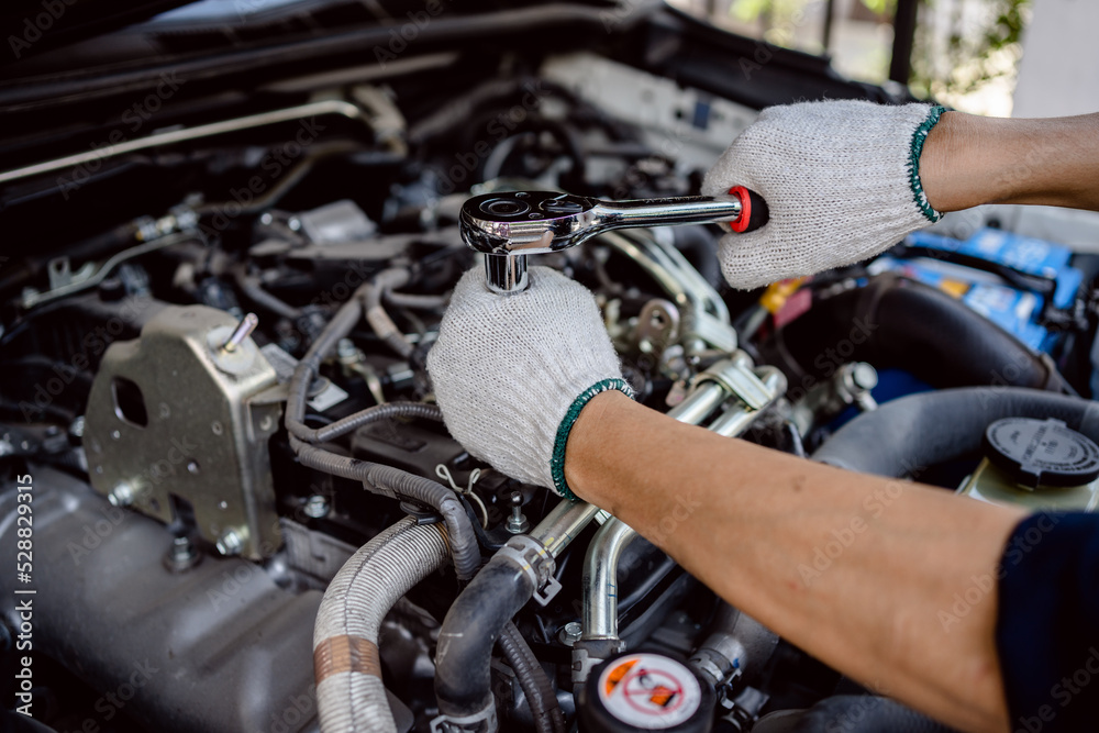 Auto mechanic repairman using a socket wrench working engine repair in the garage, change spare part, check the mileage of the car, checking and maintenance service concept. Auto mechanic repairman using a socket wrench working engine repair in the garage, change spare part, check the mileage of the car, checking and maintenance service concept.