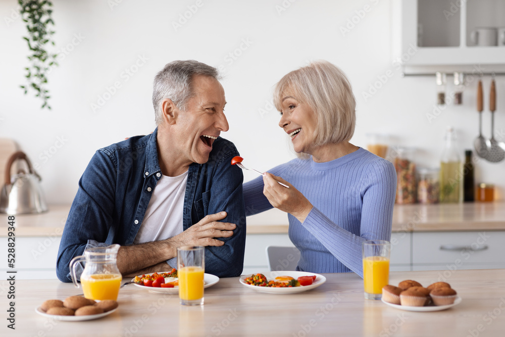 Happy senior woman having lunch with her husband at home