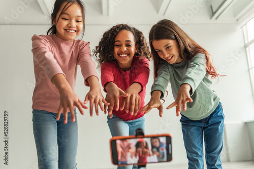 Three Multiethnic Blogger Girls Posing Making Video On Cellphone Indoors