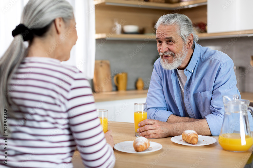 Senior Married Couple Chatting While Having Breakfast Together In Kitchen Senior Married Couple Chatting While Having Breakfast Together In Kitchen