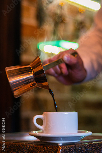 Serving turkish coffee on a cup using a copper cup