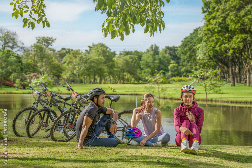 Obraz premium LGBTQ friendsresting by lake after riding bicycle together for exercise in park