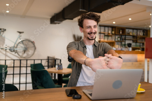 One man stretch while taking a brake from remote online work at cafe © Miljan Živković