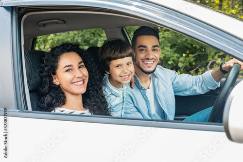 Happy millennial middle eastern family with child go to vacation by car and look at camera, copy space © Prostock-studio