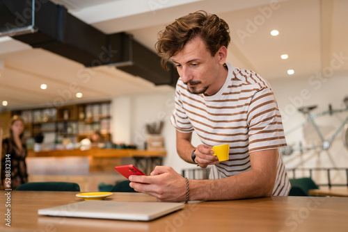 One modern caucasian man using mobile phone while stand at cafe