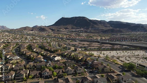 Drone ascending over suburbs in Henderson Nevada with highway and mountains in the background blue sky 60fps