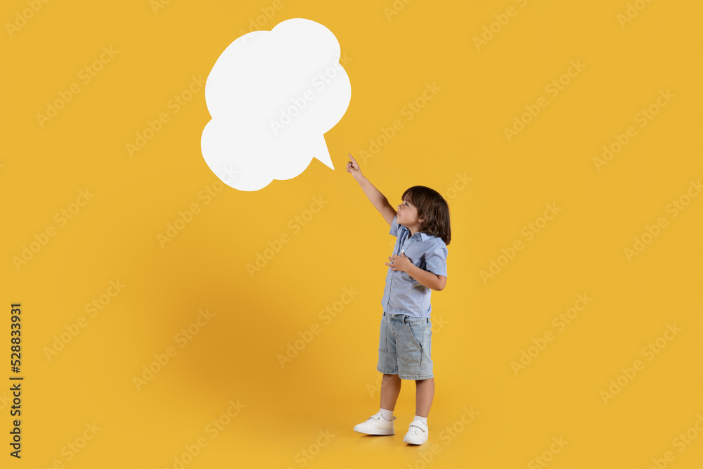 Adorable little boy pointing at empty speech bubble, feeling excited of news, full length, free space Adorable little boy pointing at empty speech bubble, feeling excited of news, full length, free space