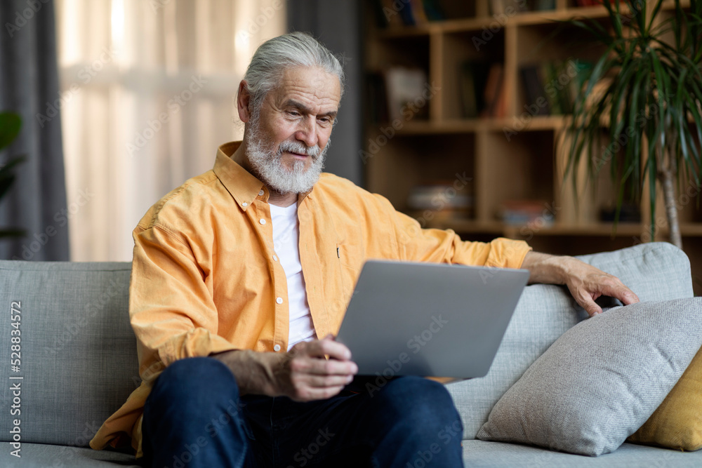 Happy senior man using modern laptop at home Happy senior man using modern laptop at home