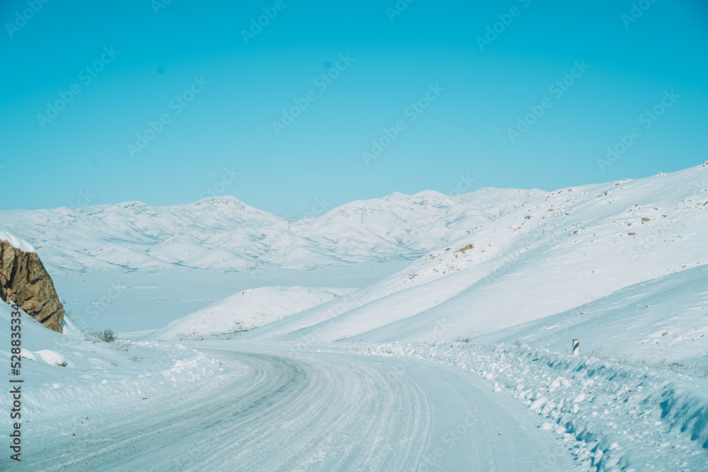Snowy road among fields and mountains.