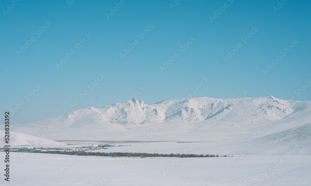 Village among snowy mountains and fields.