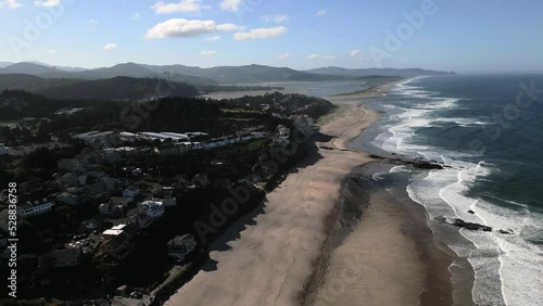 Aerial drone view of the coastline at Lincoln Beach, Oregon, featuring sandy shoreline, rolling ocean waves, and rugged coastal scenery. The elevated perspective highlights natural patterns, open spac