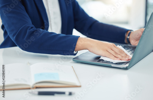 Business person clean laptop with tissue, care for desk and workspace and protect from covid at table in corporate office. Employee, worker and professional cleaning dust from keyboard at work
