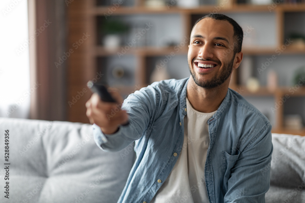 Portrait Of Cheerful Young African American Man Watching TV At Home Portrait Of Cheerful Young African American Man Watching TV At Home