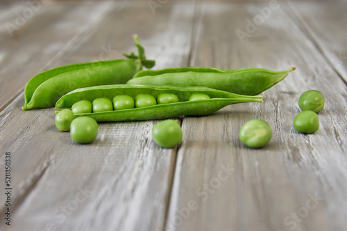 Opened pods of fresh green peas on wooden background