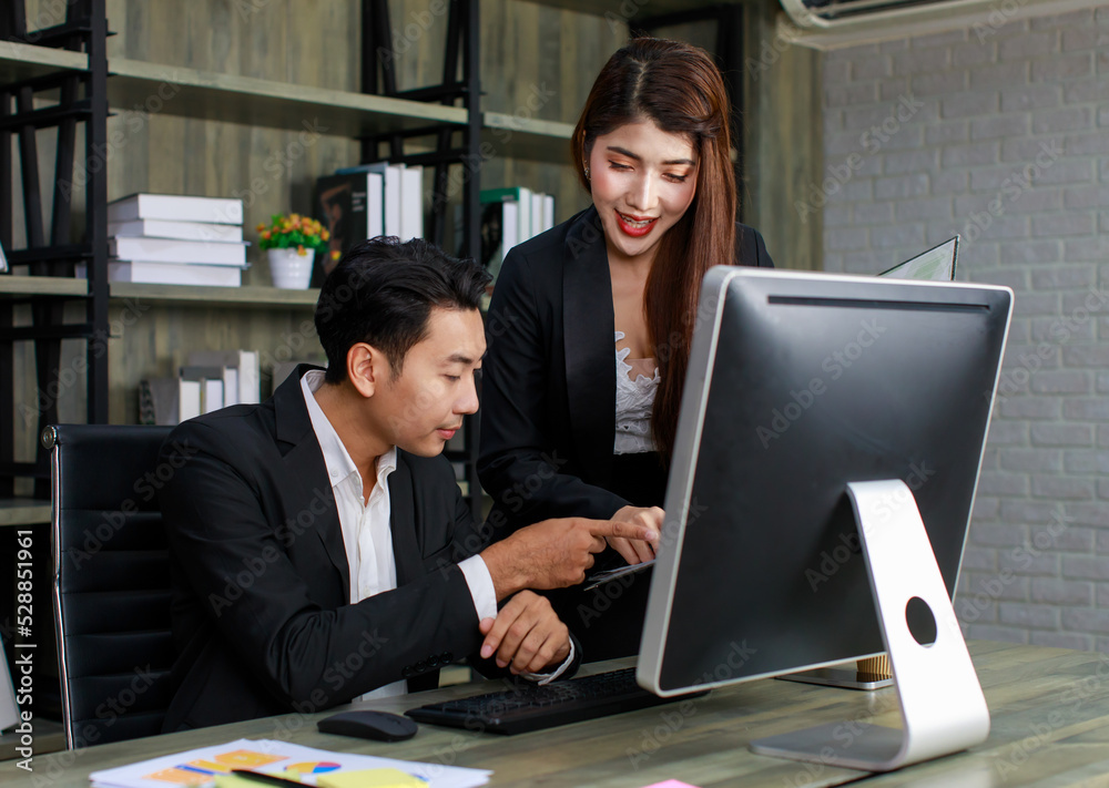 Millennial Asian young professional successful male businessman ceo entrepreneur in formal suit sitting looking reading checking paperwork document in folder from female businesswoman secretary Millennial Asian young professional successful male businessman ceo entrepreneur in formal suit sitting looking reading checking paperwork document in folder from female businesswoman secretary