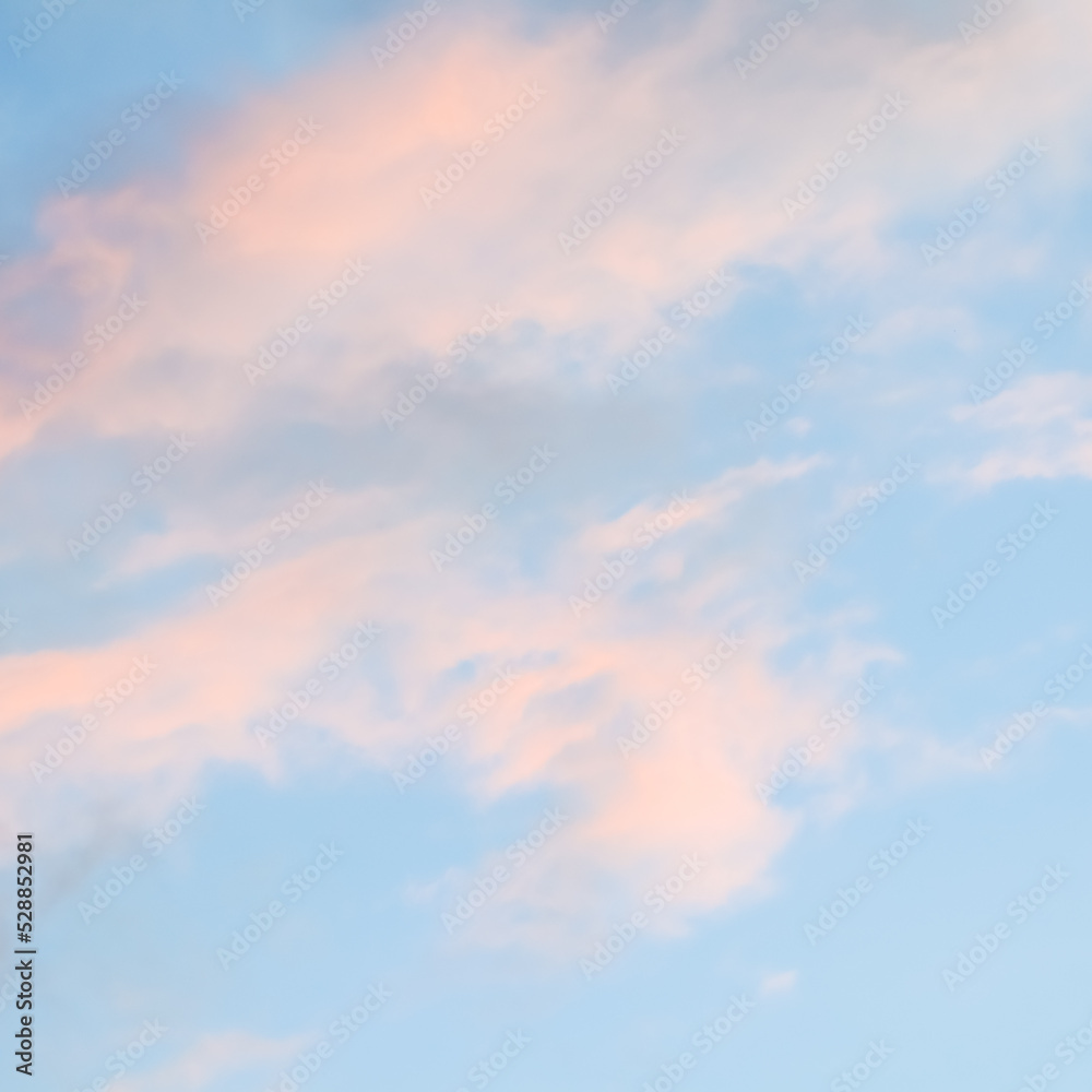 Blue sky background with pale pink clouds at sunset